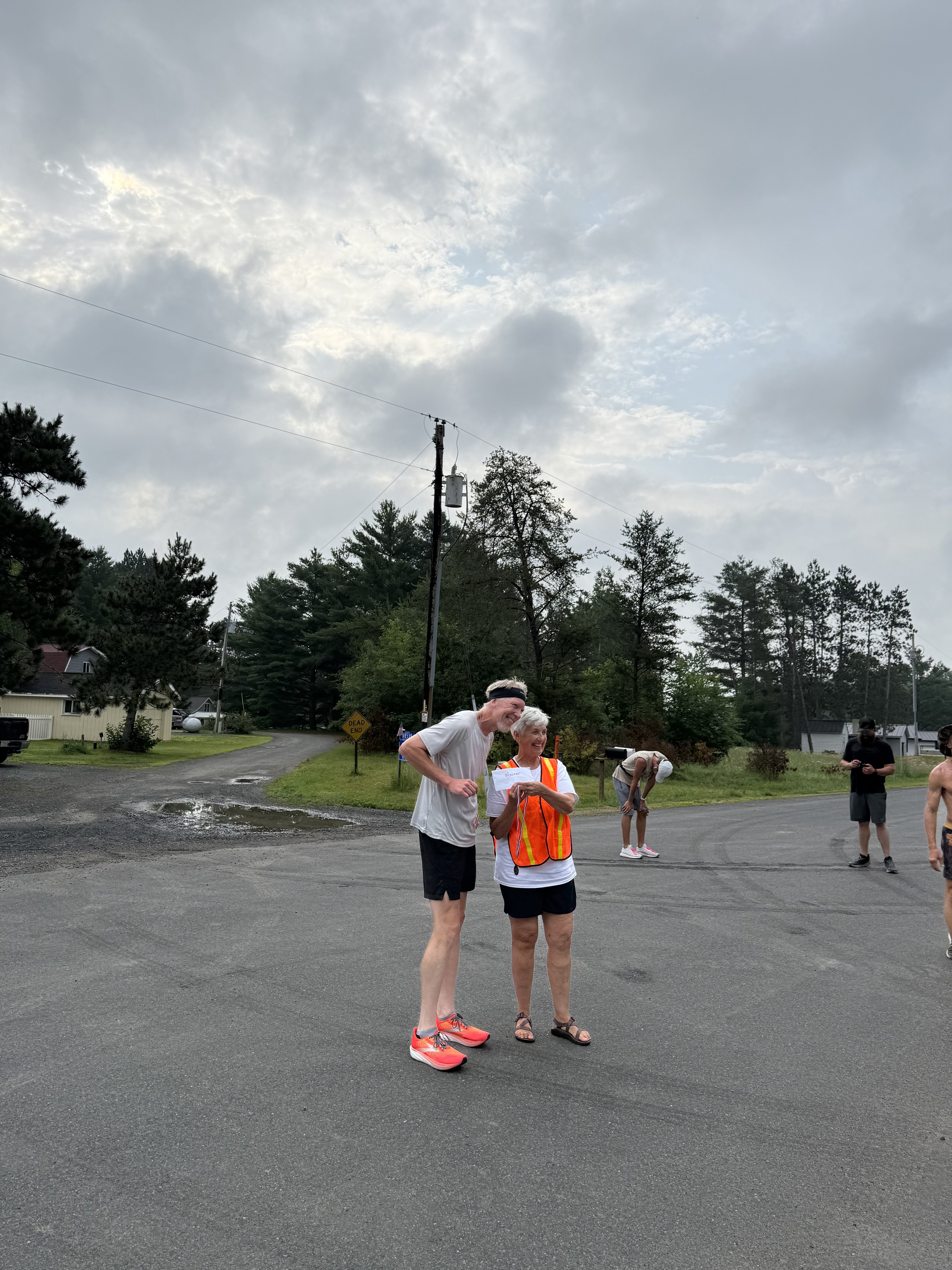 Volunteer in orange safety vest cheering on runners along the course